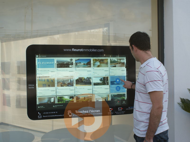 Image écran vitrine tactile installée dans une agence immobilière du groupe FLEUROT IMMOBILIER
